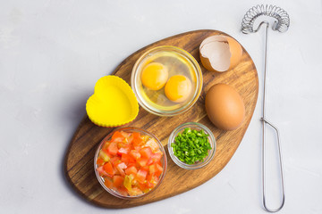 Vegetables and eggs on wooden board - breakfast mini frittatas cooking. 
