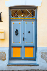 Naklejka premium A beautiful vintage blue door with orange inserts with an old handle and a lock. The same doors you can find in historical centers of many european cities.