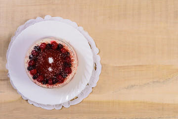 Pie with berries on a white plate lies on a wooden table