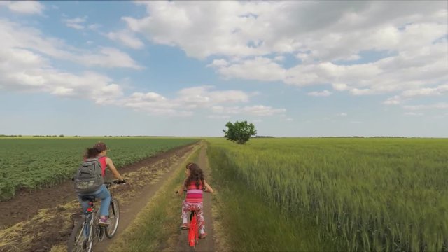A sports family on bicycles. Mom with a child in the field on bicycles.
