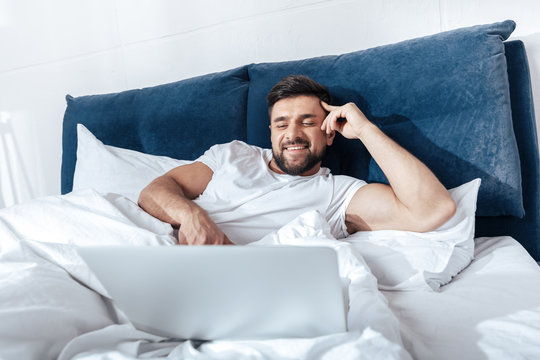 Young Man Using Laptop In Bed