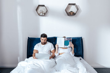 Portrait of young loving couple reading in bed