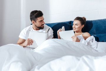 Obraz premium Portrait of young loving couple reading in bed