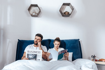 Portrait of young loving couple reading in bed
