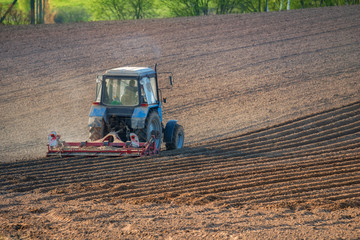 Tractor with cultivator handles field before planting. Preparing land for sowing at spring, farmer in tractor