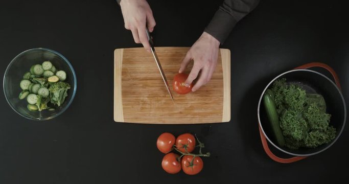 Cutting tomatoes for dishes on the table. Vegetables during the cooking process dishes. Vegetables for healthy eating and dieting. Top view.