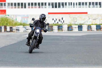 Motorcycle rider wearing in protective leather and textile racing suit practice on the track