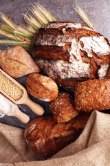 Different kinds of bread and bread rolls on board from above. Ki