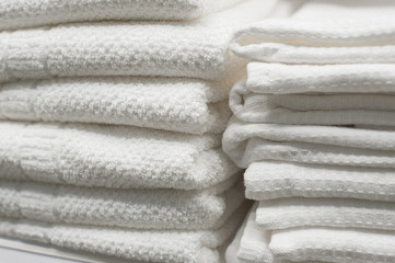 White towels stacked on a shelf in the closet