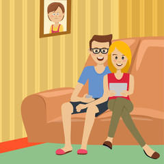 Teenage couple sitting on sofa with smartphone and tablet at home