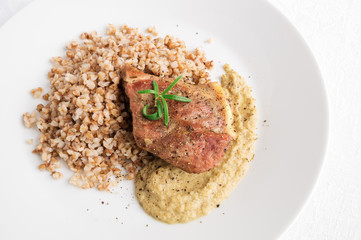 pork fillet decorated with rosemary garnished with buckwheat porridge, and onion sauce