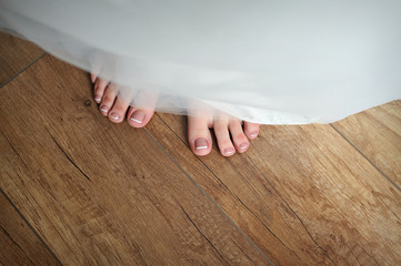 bride legs with a pedicure and a wedding dress in the wedding morning