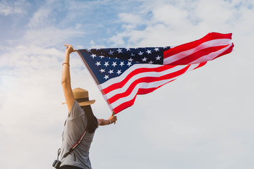 Young asian woman holding American flag on blue sky background