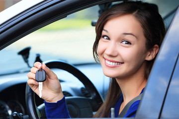 Beautiful young smiling happy girl shows the car key in her hand