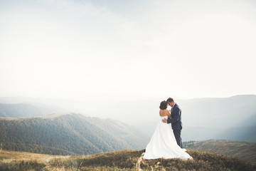 Happy beautiful wedding couple bride and groom at wedding day outdoors on the mountains rock. Happy...