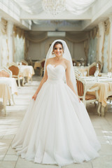 Fototapeta premium Beautiful bride wearing fashion wedding dress with feathers with luxury delight make-up and hairstyle, studio indoor photo shoot