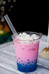 bubble tea in pink and blue color in a plastic Cup with a straw. The top is sprinkled with marshmallows.Soft, beautiful colors