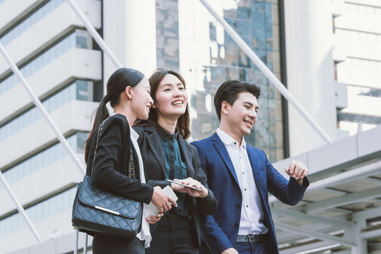 Group of happy Asian business colleagues laughing and talking enjoy outside the office.