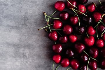 Deep dark cherries fruit pattern on gray concrete background. Copyspace. 