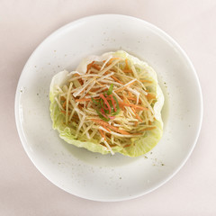 Fresh Coleslaw salad served in a salad “bowl”, decorated with herbs, placed on white plate, light background, isolated