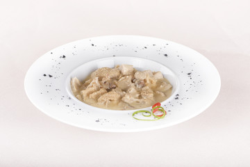 Tripe soup, served with garlic sauce – “mujdei” and horseradish sauce, decorated with green and red leafs, placed on white plate, light background, isolated