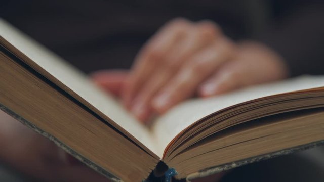Hand and book: reading a book and holding your fingers along the lines. A woman's hand holds a book and moves her fingers along the page while reading. The reader of the book holds
