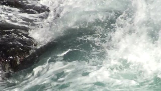Surf waves near a rocky shore. Seawater foams and smashes against rocks. HD 1920x1080 Video Clip