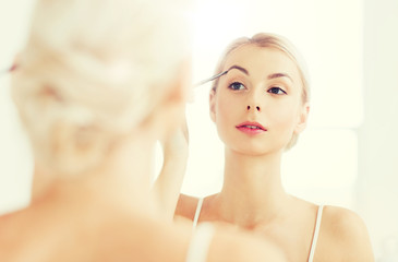 woman with brush doing eyebrow makeup at bathroom