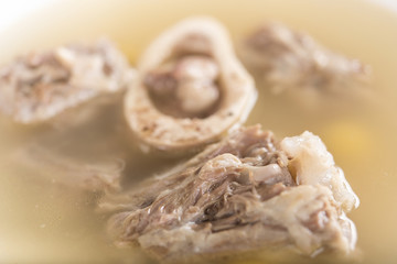Bone marrow soup, served in a white bowl, light background, isolated