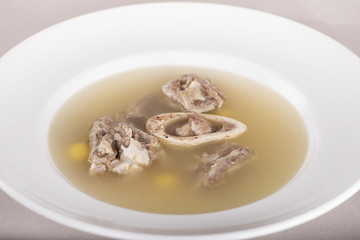 Bone marrow soup, served in a white bowl, light background, isolated