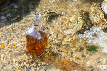 Bottle of whiskey cooled in the mountain brook