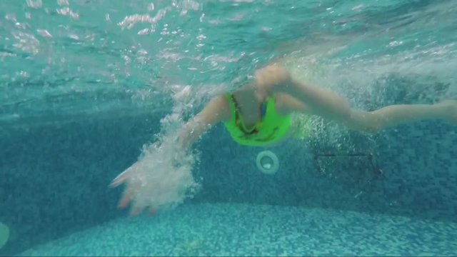 Joyful child swims in the pool under water. Slow motion