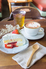coffee cup and delicious cake strawberry and relax time moblie on table in coffee shop