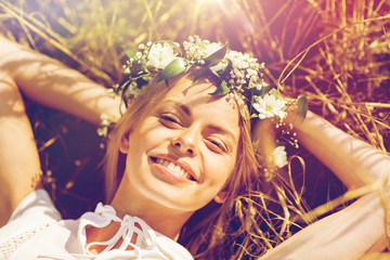 happy woman in wreath of flowers lying on straw