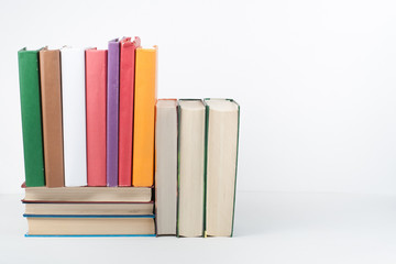 Book stack, hardback colorful books on wooden table, white background. Back to school. Copy space for text. Education business concept.