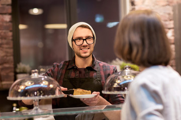man or barman with cakes serving customer at cafe