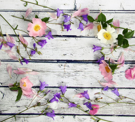 Bellflower flowers, wild rose and pink petals on a wooden background, rustic style