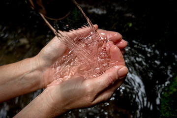 Quellwasser sauber und klar sprudelt in Frauenhänden