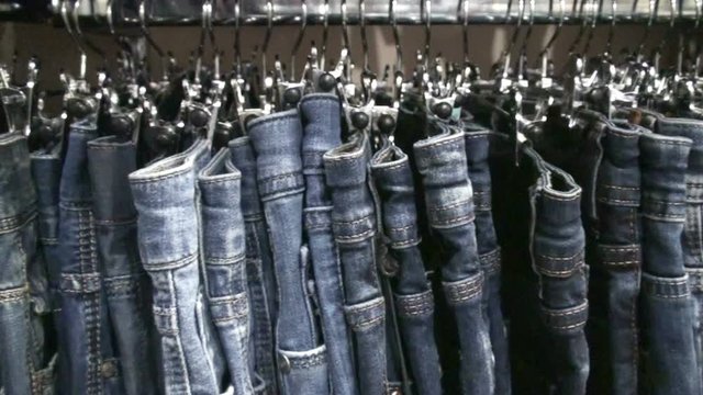 Jeans hanging on hangers on the rack in the clothing store. HD 1920x1080 Video Clip