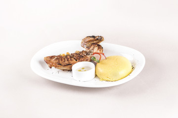 Chicken half breast and wing with polenta and garlic sauce “mujdei”, decorated with fresh leafs, light background, isolated