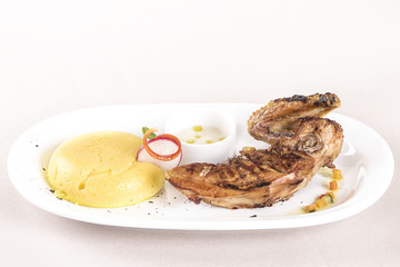 Chicken half breast and wing with polenta and garlic sauce “mujdei”, decorated with fresh leafs, light background, isolated