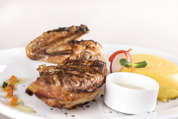 Chicken half breast and wing with polenta and garlic sauce “mujdei”, decorated with fresh leafs, light background, isolated
