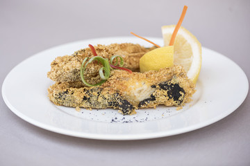 Grilled carp, served with lemon and decorated with radish and fresh leafs, light background, isolated