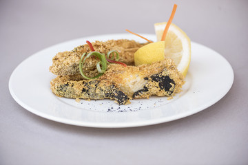 Fried carp with lemon, decorated with herbs, isolated on light background, white plate