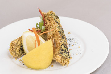 Grilled carp, served with lemon and decorated with radish and fresh leafs, light background, isolated