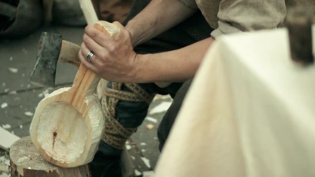Carpenter hewing wooden bailer with a hatchet