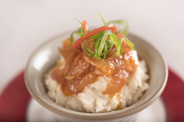 Beans puree with sweet onion and tomato sauce, served in a bowl on a red and white plate, decorated with herbs, light background, isolated