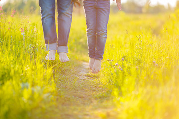 A young married couple jumps high on a trail laid in a rush of juicy grass on a meadow. Legs of a man and women hang in the air