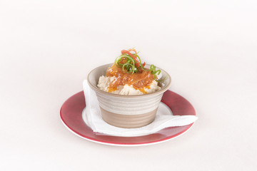 Beans puree with sweet onion and tomato sauce, served in a bowl on a red and white plate, decorated with herbs, light background, isolated