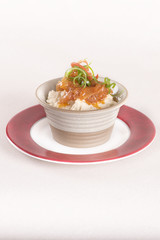 Beans puree with sweet onion and tomato sauce, served in a bowl on a red and white plate, decorated with herbs, light background, isolated